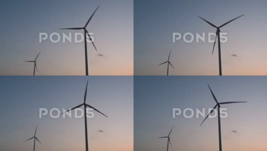 能源，风力涡轮机在日落时分的蓝色天空中的剪影，清洁能源高清在线视频素材下载
