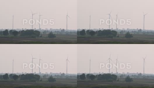 风力涡轮机在下午旋转，因为有树木的农田创造了一个高清在线视频素材下载