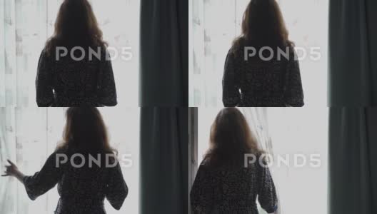 在家中，穿着浴袍的深色头发女人站在窗边的背影高清在线视频素材下载