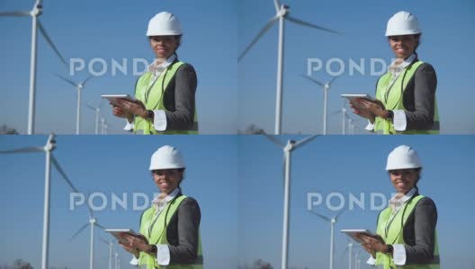 戴安全帽的女人对着风力涡轮机高清在线视频素材下载