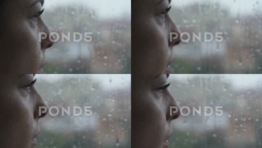抑郁，悲伤-女人站在窗前看着雨滴在玻璃上滑落高清在线视频素材下载
