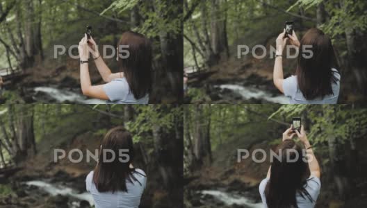 游客女孩使用手机拍照，小瀑布顺着岩石流下来高清在线视频素材下载