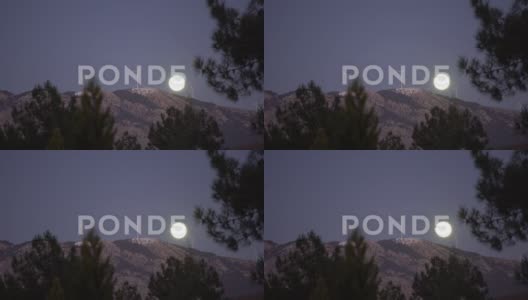 风力涡轮机在晴朗的夜晚与山后的满月一起拍摄4K高清在线视频素材下载