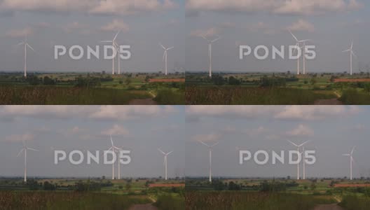 风力发电机高耸在农田上方，农民种植庄稼并照料着高清在线视频素材下载
