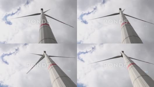 一个现代风力涡轮机在多云的天空前旋转4k30fps视频高清在线视频素材下载