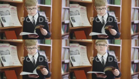 戴眼镜的男孩站在书架前看书高清在线视频素材下载