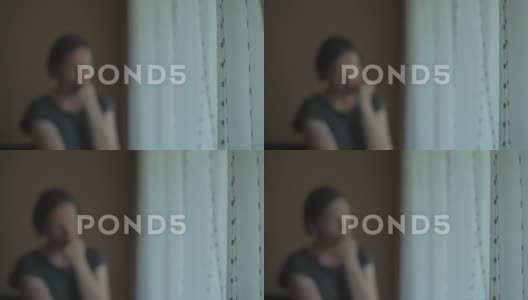 一个悲伤的女人站在窗边看着窗外高清在线视频素材下载