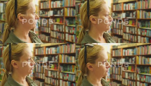 一位女性站在图书馆内，背景是书架和书架4K高清在线视频素材下载