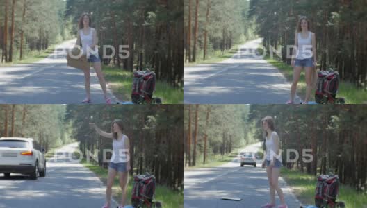年轻美丽的女人背着一个背包站在路边搭便车高清在线视频素材下载