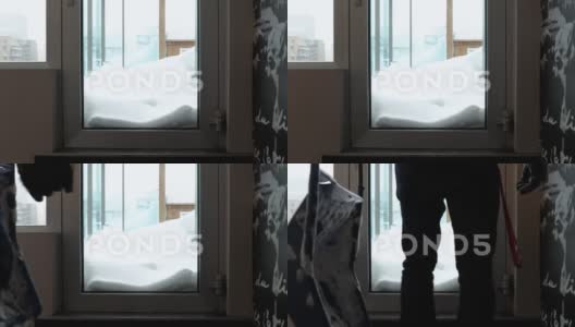一个拿着铲子的男人站在窗户前等待雪。带着高清在线视频素材下载