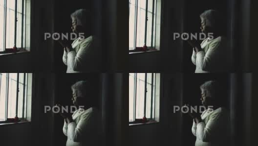 一个精神上的年轻非洲女人站在窗户旁向上帝祈祷高清在线视频素材下载