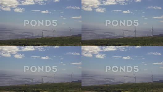 4K风力涡轮机在俯瞰浩瀚海洋的山坡上旋转高清在线视频素材下载