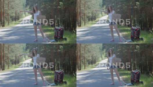 年轻美丽的女人背着背包站在路边搭便车高清在线视频素材下载
