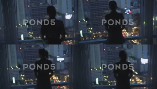 晚上看城市的女人影子，站在家里的窗户旁高清在线视频素材下载