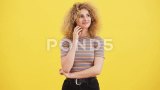 一位卷发金发女子独自站在黄色墙壁前，正在思考着某件事情高清在线视频素材下载
