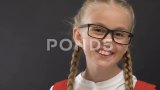 快乐的女学生戴着眼镜对着黑板对着镜头微笑，教育高清在线视频素材下载