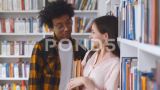 年轻的多民族夫妇站在大学图书馆的书架前高清在线视频素材下载