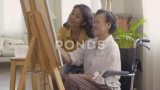 女教师教高年级妇女在客厅画画。高清在线视频素材下载